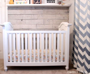 The pallet wall and chevron curtains in this baby boy's nursery would 