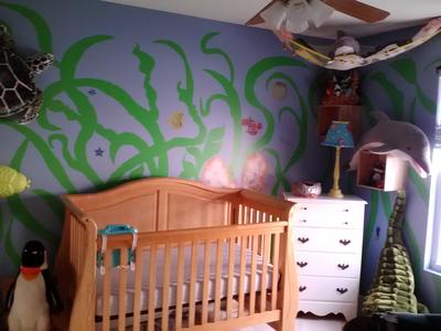 DIY under the sea ocean creatures nursery wall mural painting and a natural wood color baby crib that is close to the color of seashells.