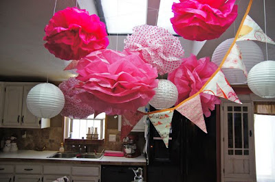 Pink and white tissue paper pom poms and party banner for a baby girl butterfly theme shower