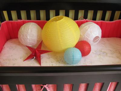 Colorful paper lanterns and stars make super cheap nursery wall and ceiling decorations.  These look amazing with my red gingham baby bedding!