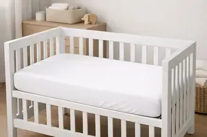Breathable mini crib mattress in a small modern nursery with a fitted sheet and simple neutral bedding