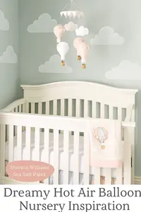dreamy hot air balloon baby girl nursery painted in Sherwin Williams Sea Salt with cloud mural and blush pink crib bedding