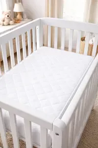 Firm mini crib mattress properly fitted inside a compact mini crib
