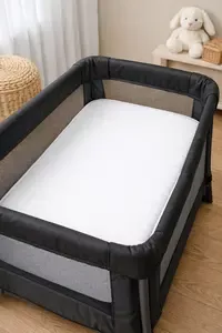 Mini portable crib mattress properly fitted inside a compact travel crib