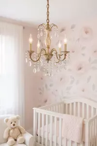 Refurbished chandelier in an elegant baby girl's nursery with soft pink and cream tones, crystal details, and warm ambient lighting.