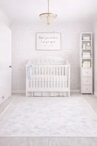 Small 8x10 nursery layout with a standard crib, slim vertical storage in a soft blush and cream palette with a small pattern floral wallpaper and rug