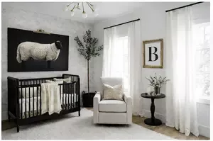 Black and white baby nursery with classic crib, patterned textiles, and soft gold accents
