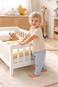 Toddler standing beside a low toddler bed during the crib to toddler bed transition stage