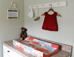 Vintage baby shoes and handknit sweater above the changing table.  The changing pad's cover matches the crib quilt made from Moda's 3 Sisters Glacé fabrics.