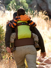 Baby in the Boba Organic Baby Carrier in back carry position hiking with dad.