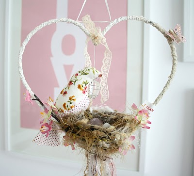 A dreamcatcher/baby crib mobile with fabric birds in a nest supported by a heart shape frame decorated with butterflies