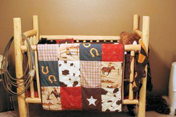 Rustic homemade pine log baby crib for a log cabin or western cowboy baby nursery with patchwork baby quilt bedding.