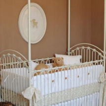 Tan vintage baby girl nursery with iron crib antique bedding set and silhouette wall decorations