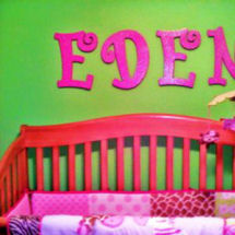 Hot pink painted wooden letters spelling a baby girl's name on neon lime green nursery wall