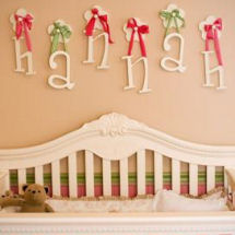 Wooden wall letters for a pink and green nursery that spell a baby girl's name hung by ribbons
