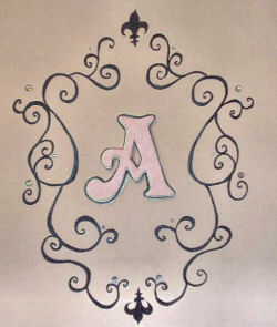 Hand painted black scrollwork and fleur de lis graphics painted on our princess' pink nursery wall framing her monogram, the letter A.