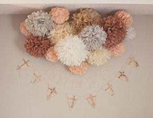 Peach taupe ivory white and gray tissue paper pom poms in the baby's nursery