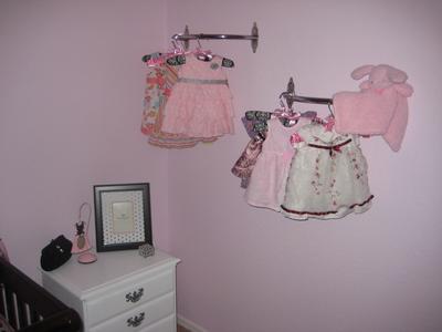 Ava's pretty dresses hung on custom made clothes racks make a pretty display on the nursery wall