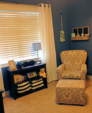 Comfortable seating and efficient storage in a baby boy nautical nursery with a navy blue wall paint color