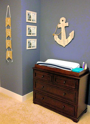 A rustic wooden anchor wall decoration in the changing area of a baby boy nautical nursery room