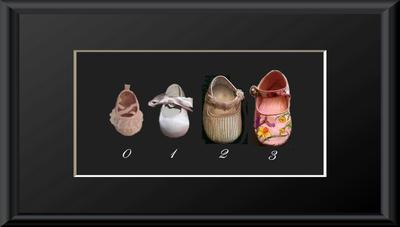 Preserved baby shoes in a growth chart shadow box picture frame