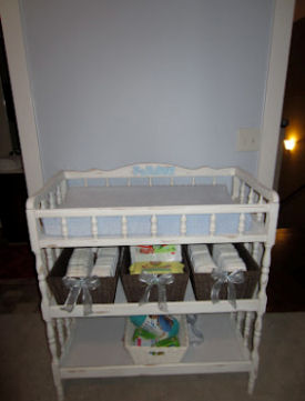 White diaper changing station with storage baskets on shelves underneath