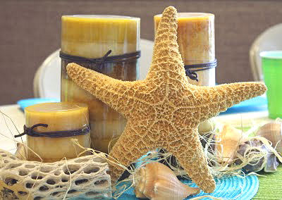 Beach theme baby shower table centerpiece with starfish seashells and pillar candles