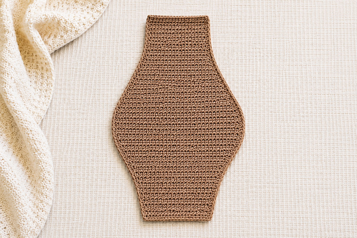 Joined unstuffed crochet bear snuggler body showing the wider belly and tapered upper and lower edges