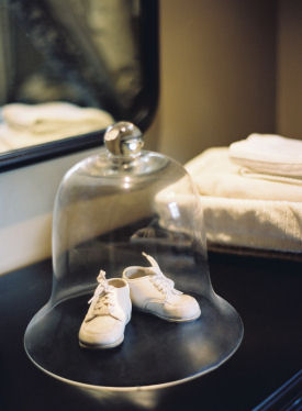 Vintage baby shoes on display in the nursery protected under a glass dome