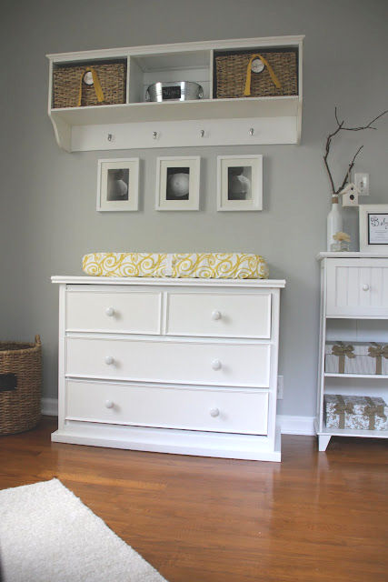 A white dresser changing table a pad covered in modern yellow and white fabric