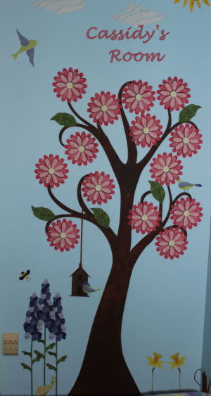 Large tree decal decorated with flowers, leaves and birds in baby girl's room.