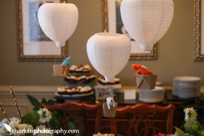 DIY hot air balloon baby shower and nursery decorations made from paper lanterns with toy animals in the basket