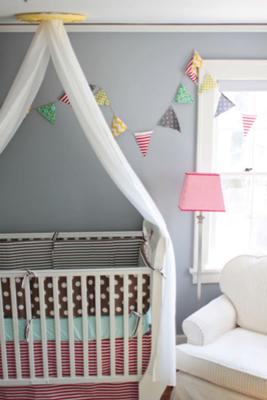 A shared baby nursery with colorful pennants and crib bedding set 