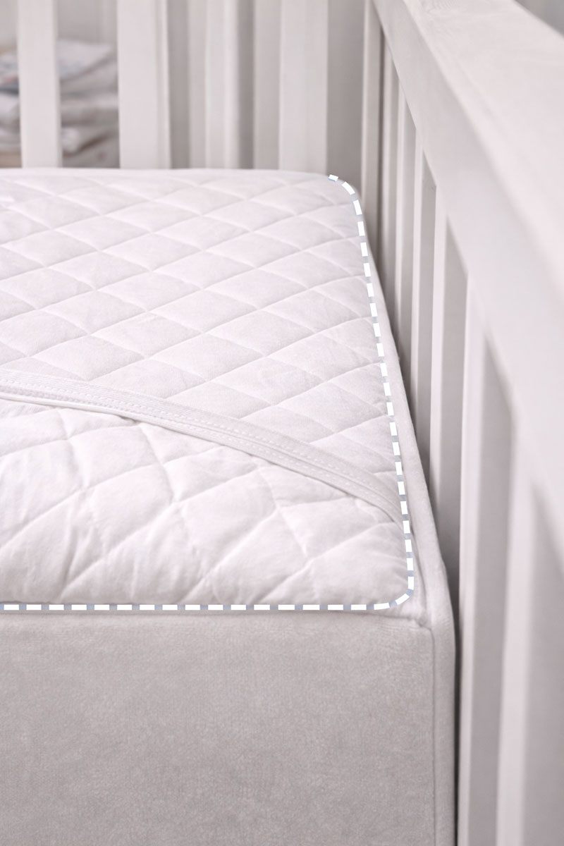 Crib mattress shown fitting tightly inside a crib frame with no visible gaps along the sides