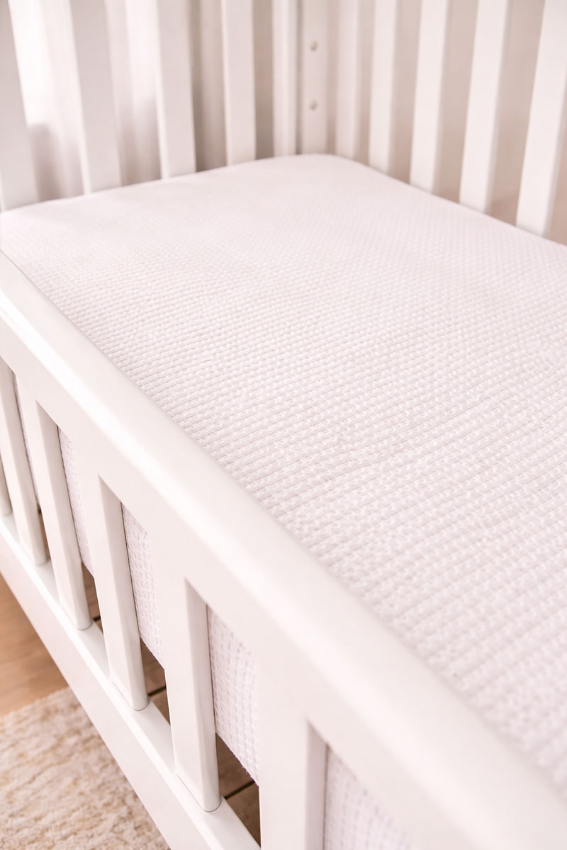 Crib mattress sitting inside a crib frame showing the edges and fit