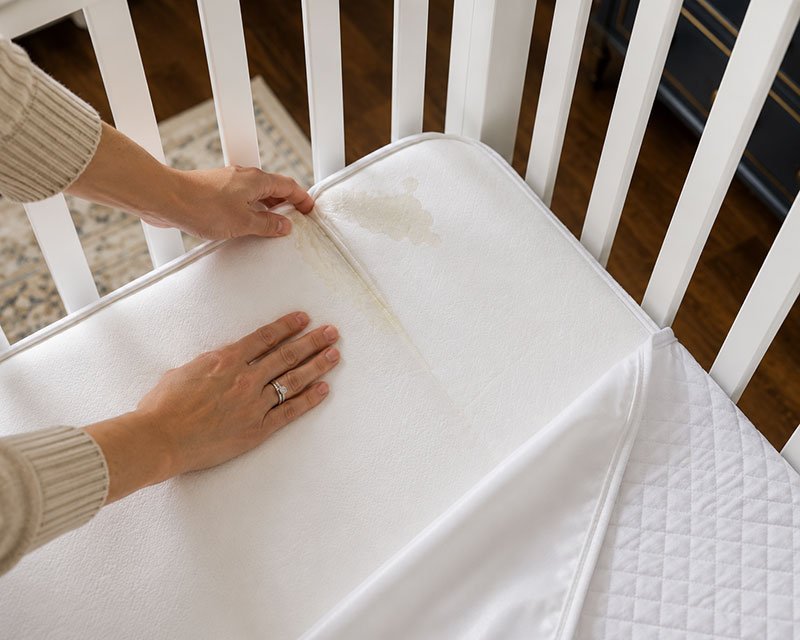 Crib mattress edge and seam being checked for moisture after a leak