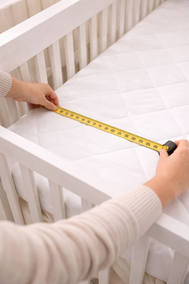 Measuring crib mattress inside crib for proper size and fit