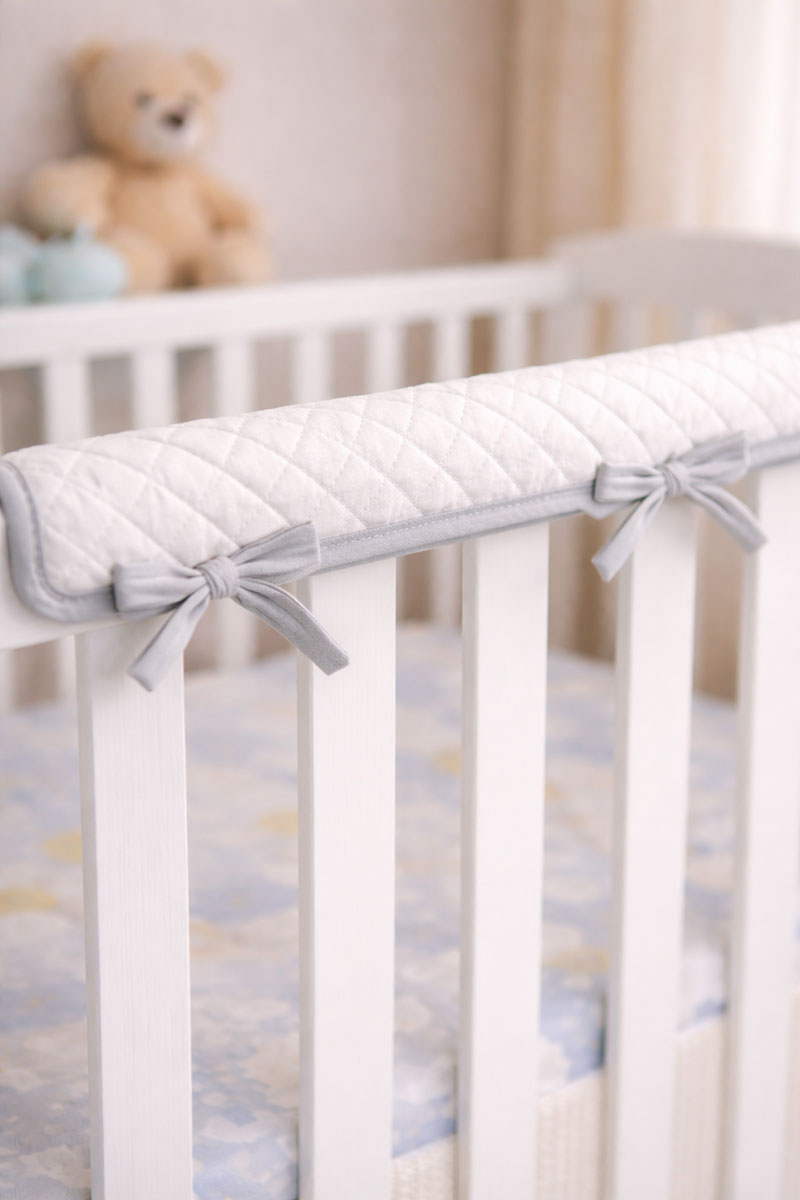 Soft crib rail cover wrapped around the top rail to reduce chewing marks