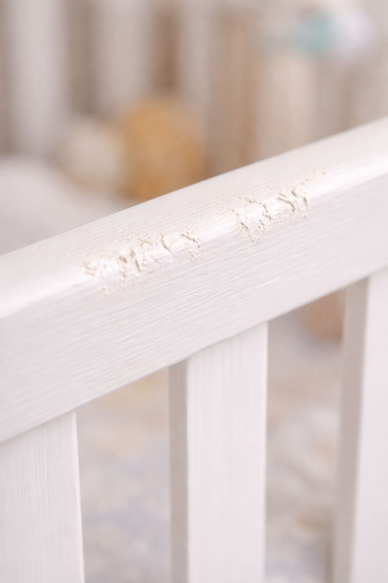 Close-up of light teeth marks on a crib rail finish from chewing