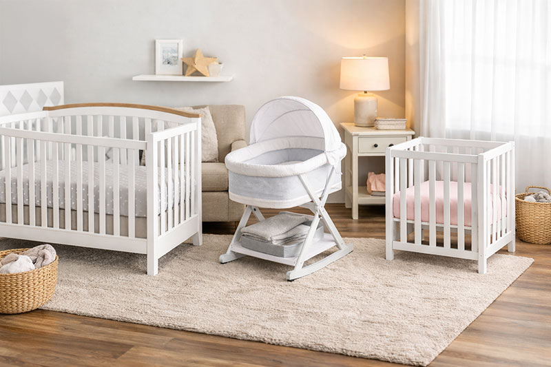 Nursery corner showing a crib, a bassinet, and a mini crib for size comparison