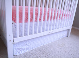 Solid white homemade ruffled crib skirt with hot pink fitted baby crib sheet in a pink white and grey girl nursery