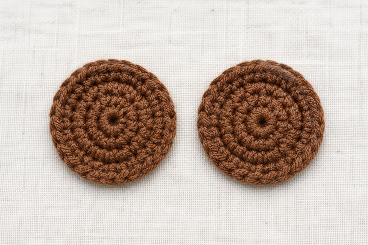 Two matching round brown crochet bear ears made with three rounds of half double crochet