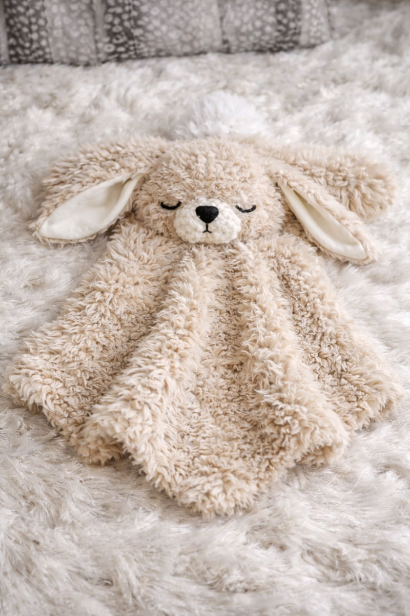 Handmade crochet bunny lovey with fuzzy yarn and soft floppy ears, styled as a baby comfort blanket lovie