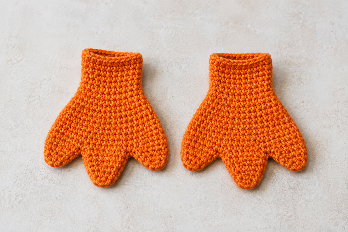 Pair of flat orange crochet duck feet with three rounded webbed toe sections on each foot