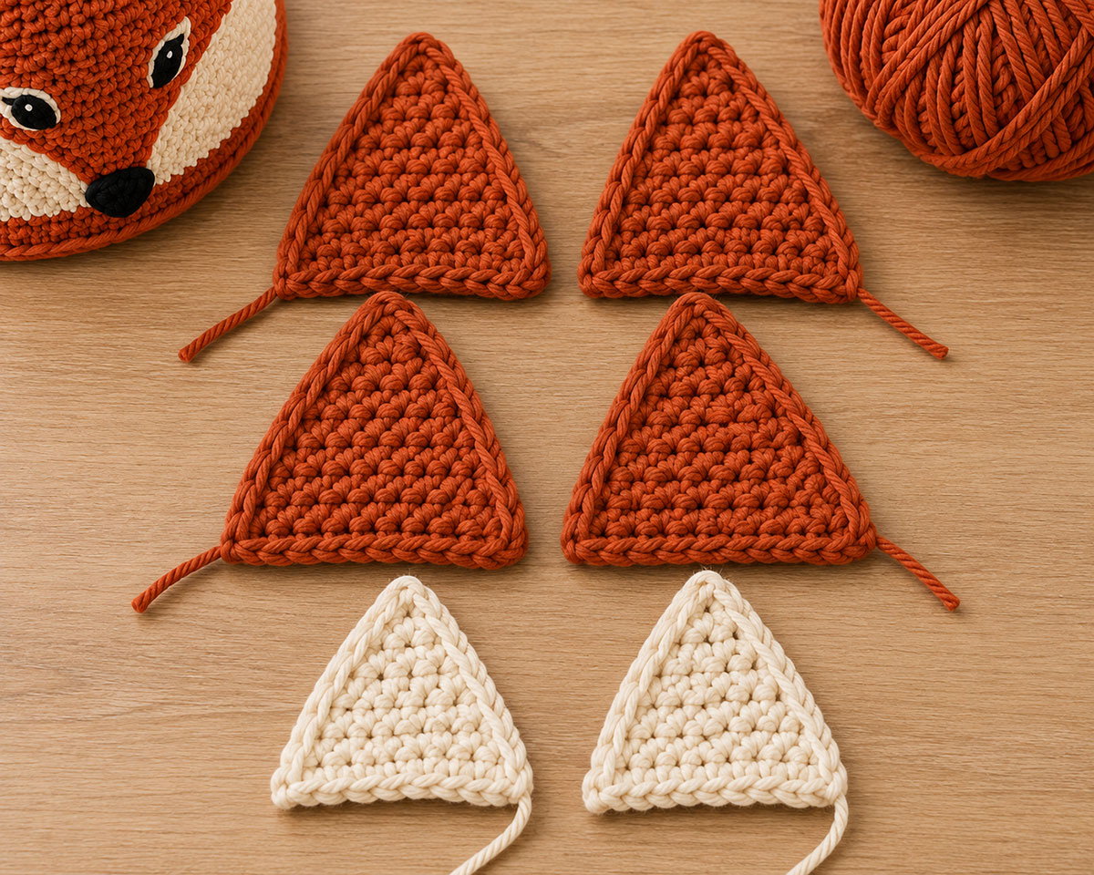 Four rust crochet fox ear panels arranged in matching pairs before assembly