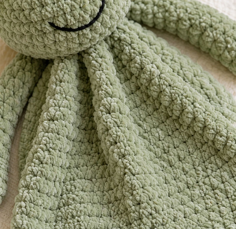 close detail of sage green chenille crochet frog lovey stitches