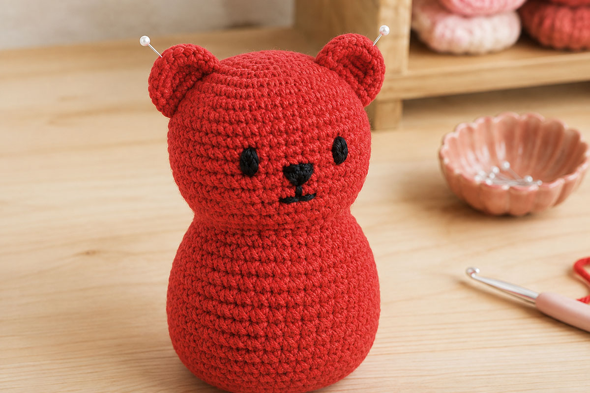 Crochet gummy bear shown from a three-quarter angle with two small round ears pinned close to the upper sides of the head before final sewing