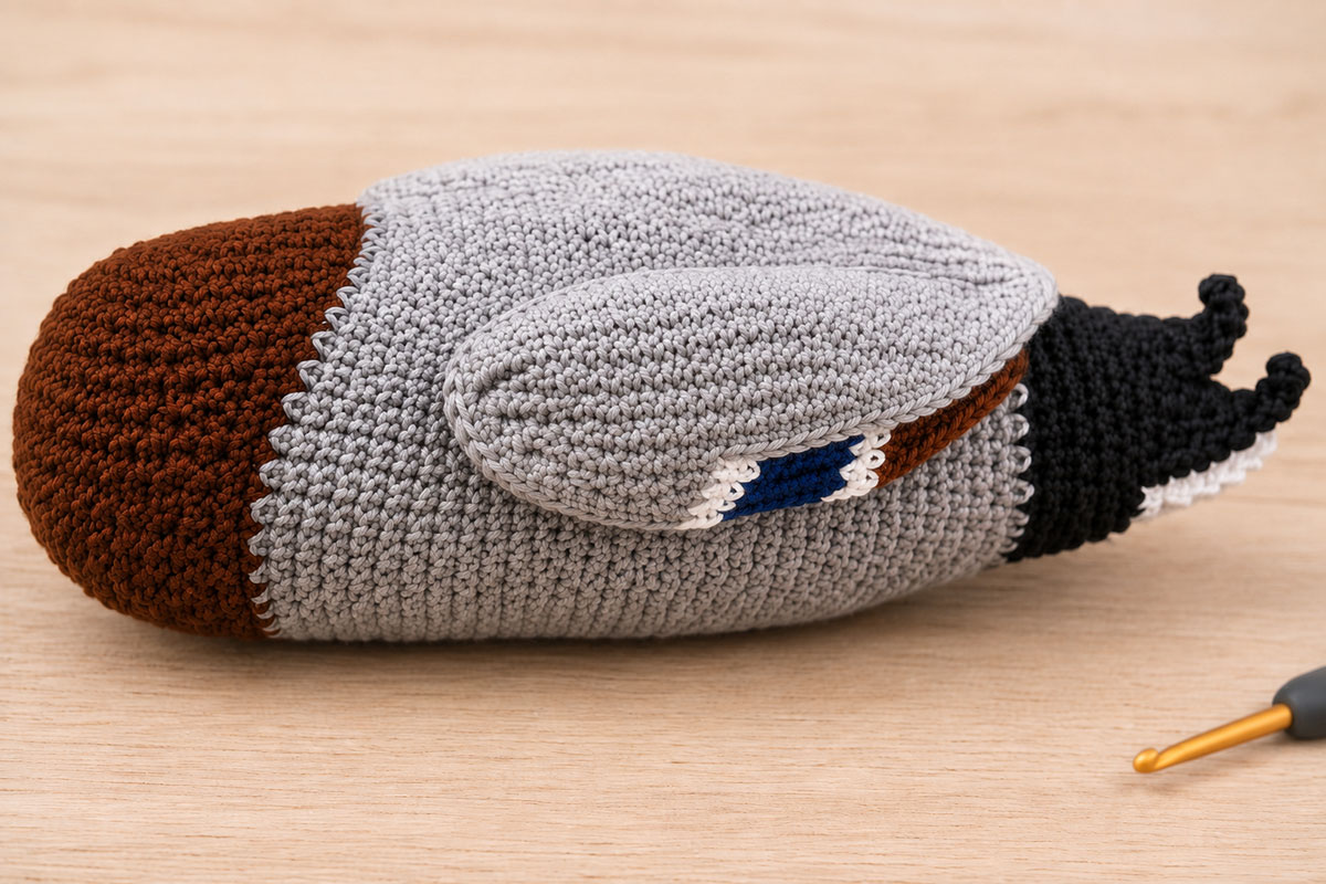 Side view of crochet mallard wing assembly showing a flat gray wing layered over a narrow blue speculum with white and chestnut details