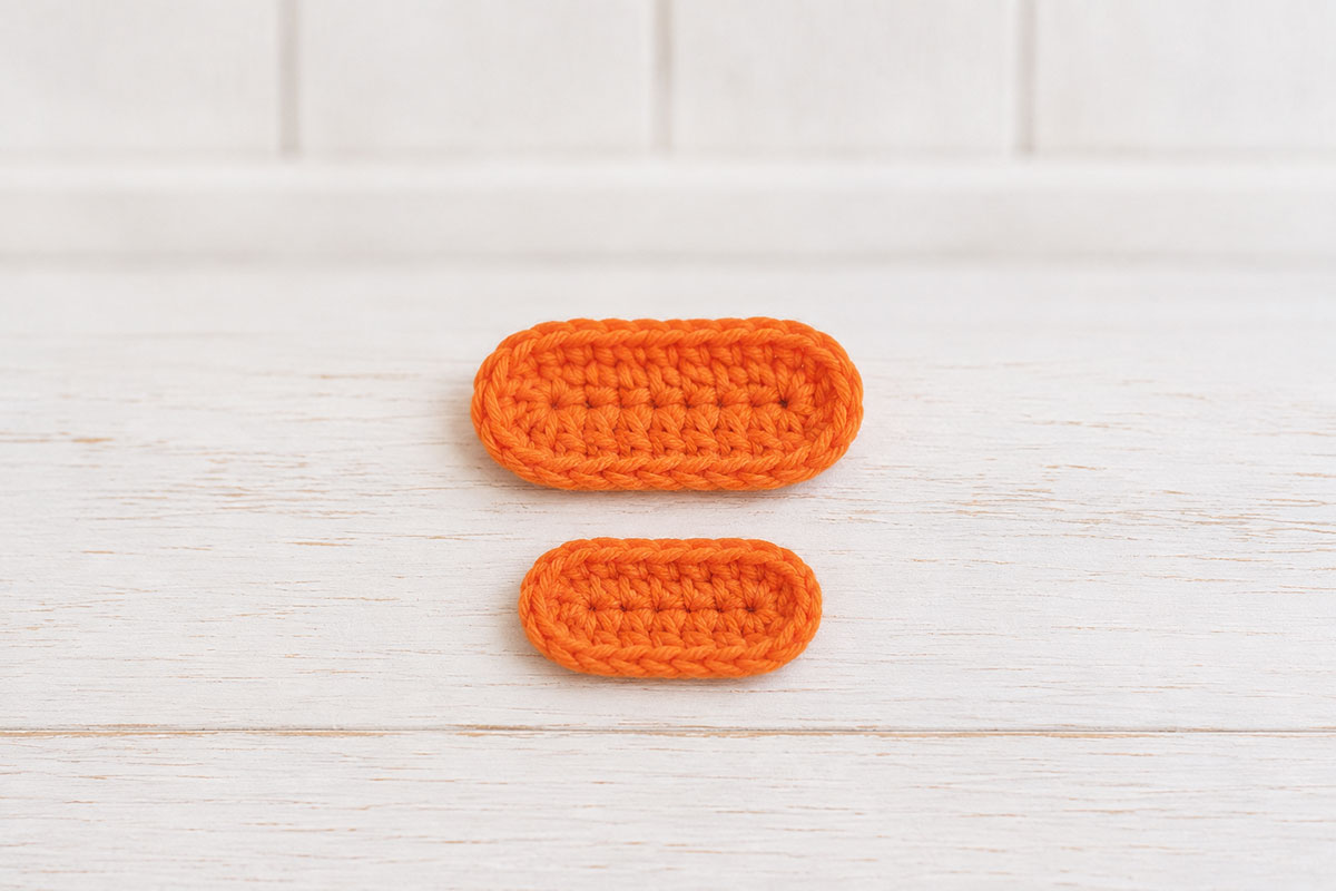 Two flat orange crochet bill pieces with a wider upper bill and slightly smaller lower bill
