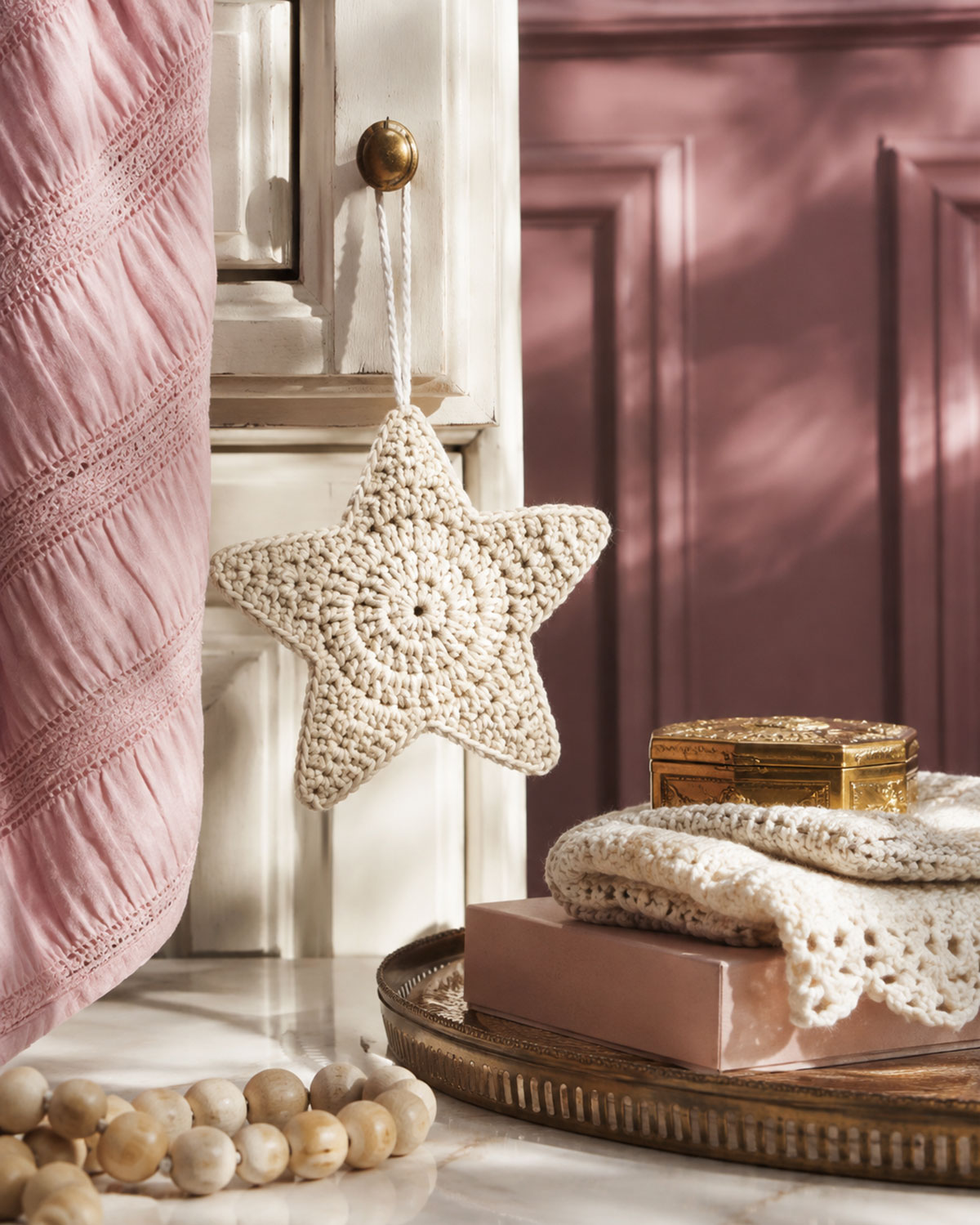 Cream five point crochet star ornament hanging by a yarn loop in an elegant holiday display